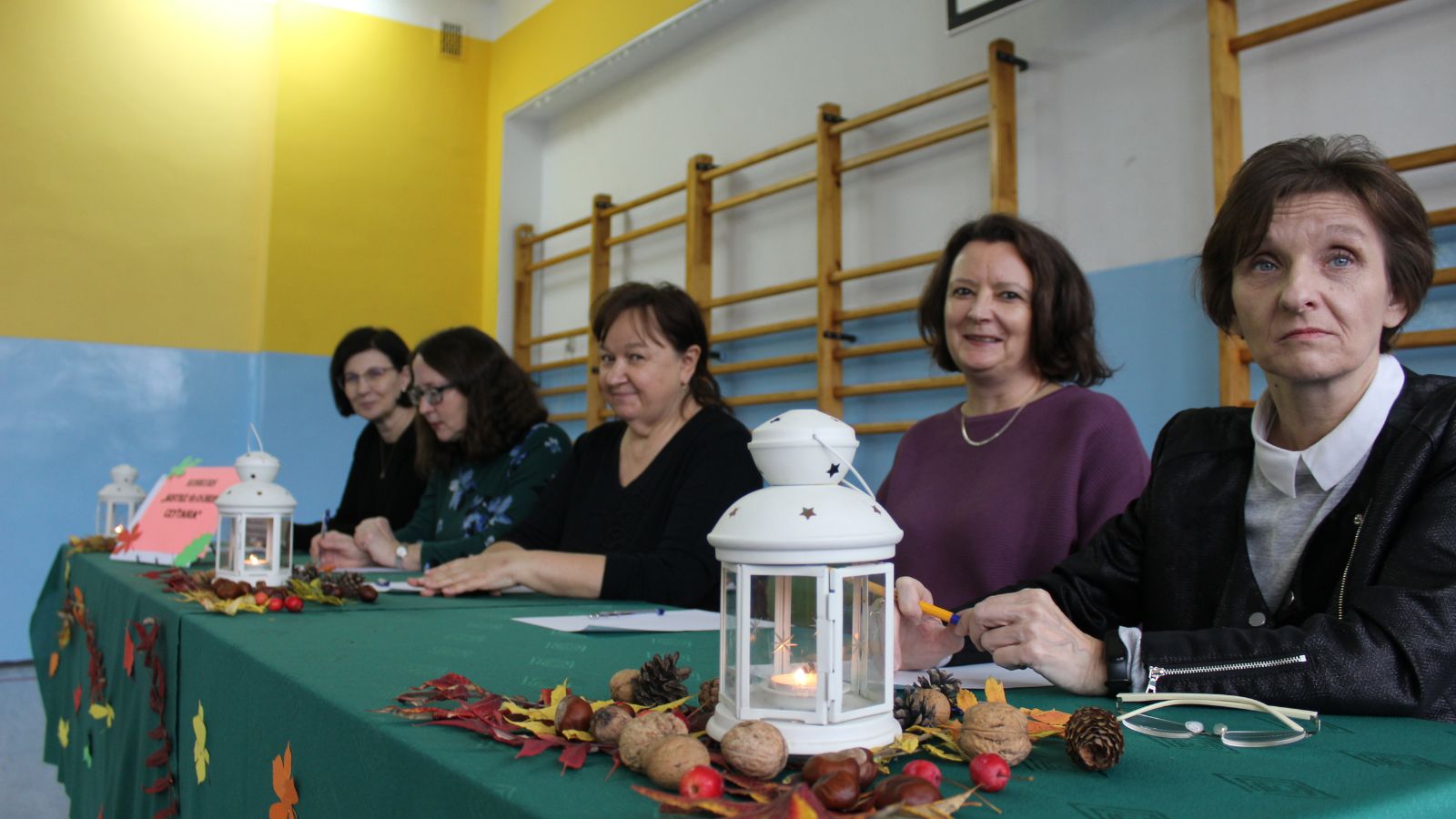Sala gimnastyczna, stół, zielony materiał, lampiony, liście, kobiety, okulary