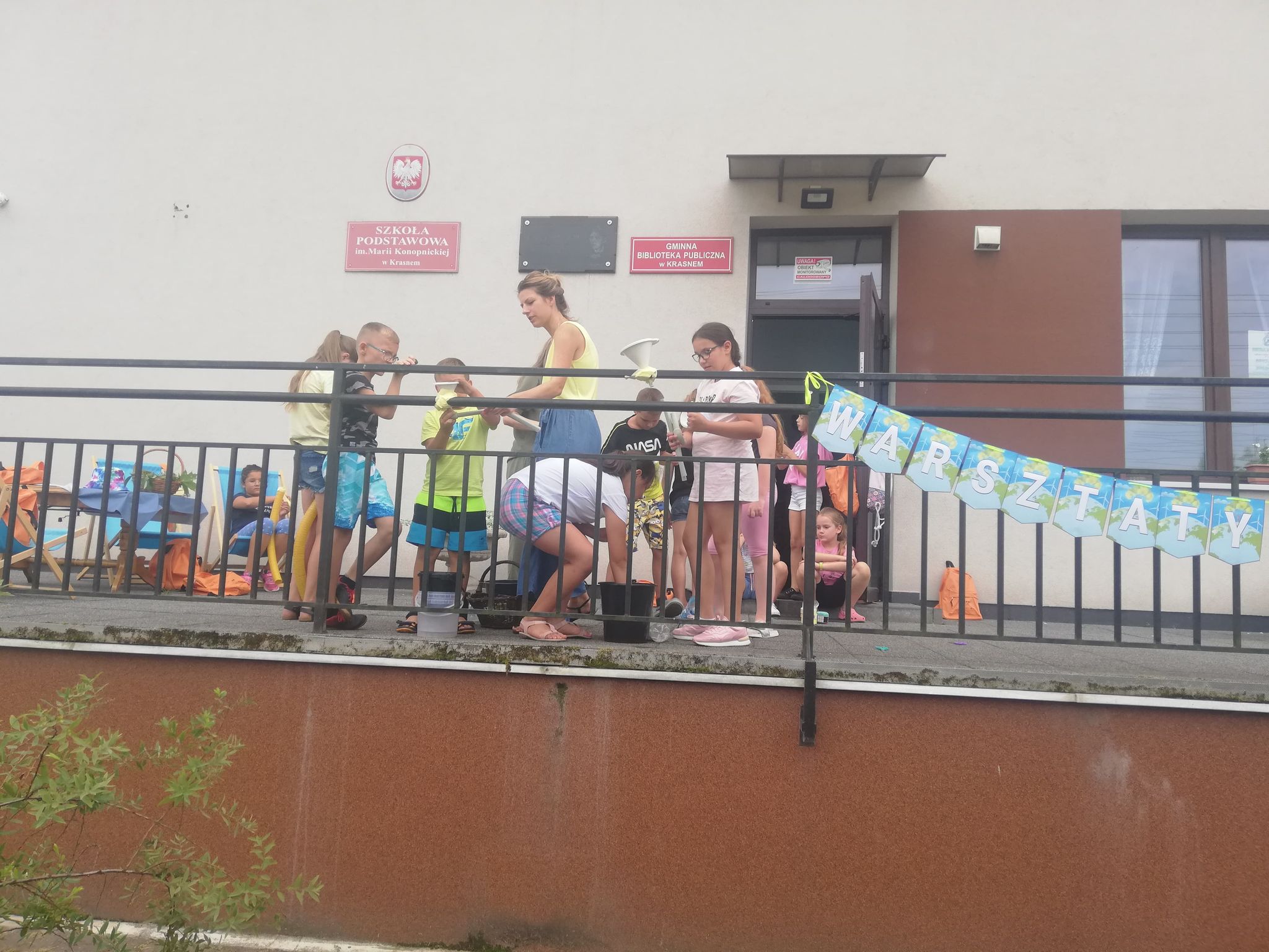 Taras przed biblioteką, drzi, okna, leżaki, stół, barierka, wiaderka, butelki, dzieci, Dorotka