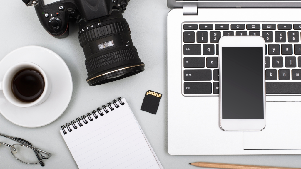 Grafika przedstawiająca komputer,notes, kawę i aparat fotograficzny